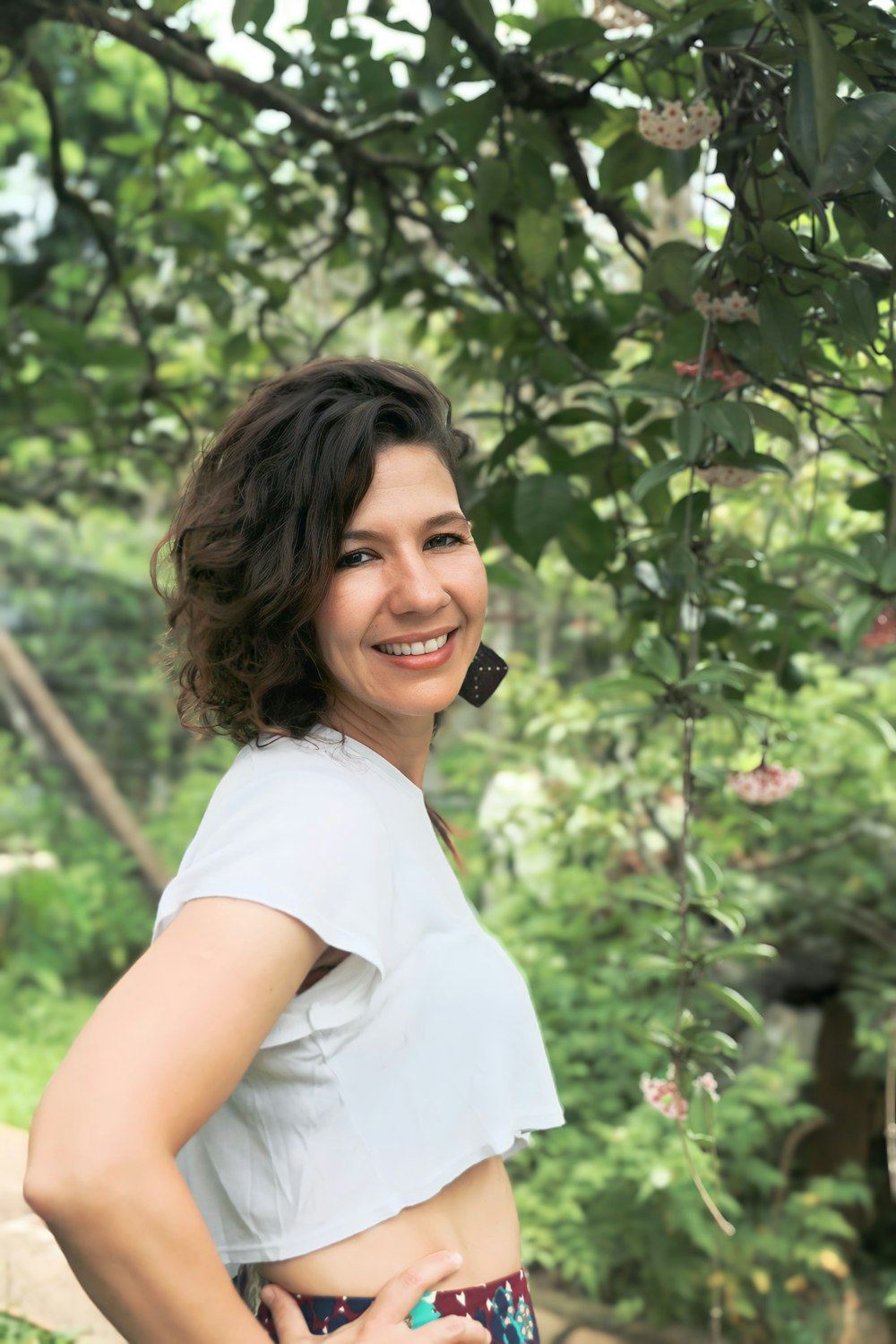 a woman standing under a tree with her hands on her hips