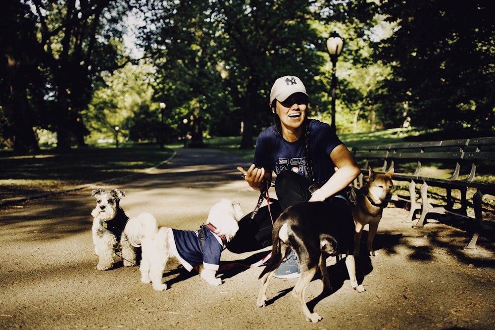 a woman sitting on a bench with three dogs