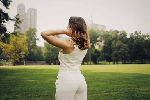 a woman in a white jumpsuit standing in a park