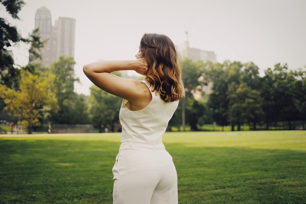 a woman in a white jumpsuit standing in a park