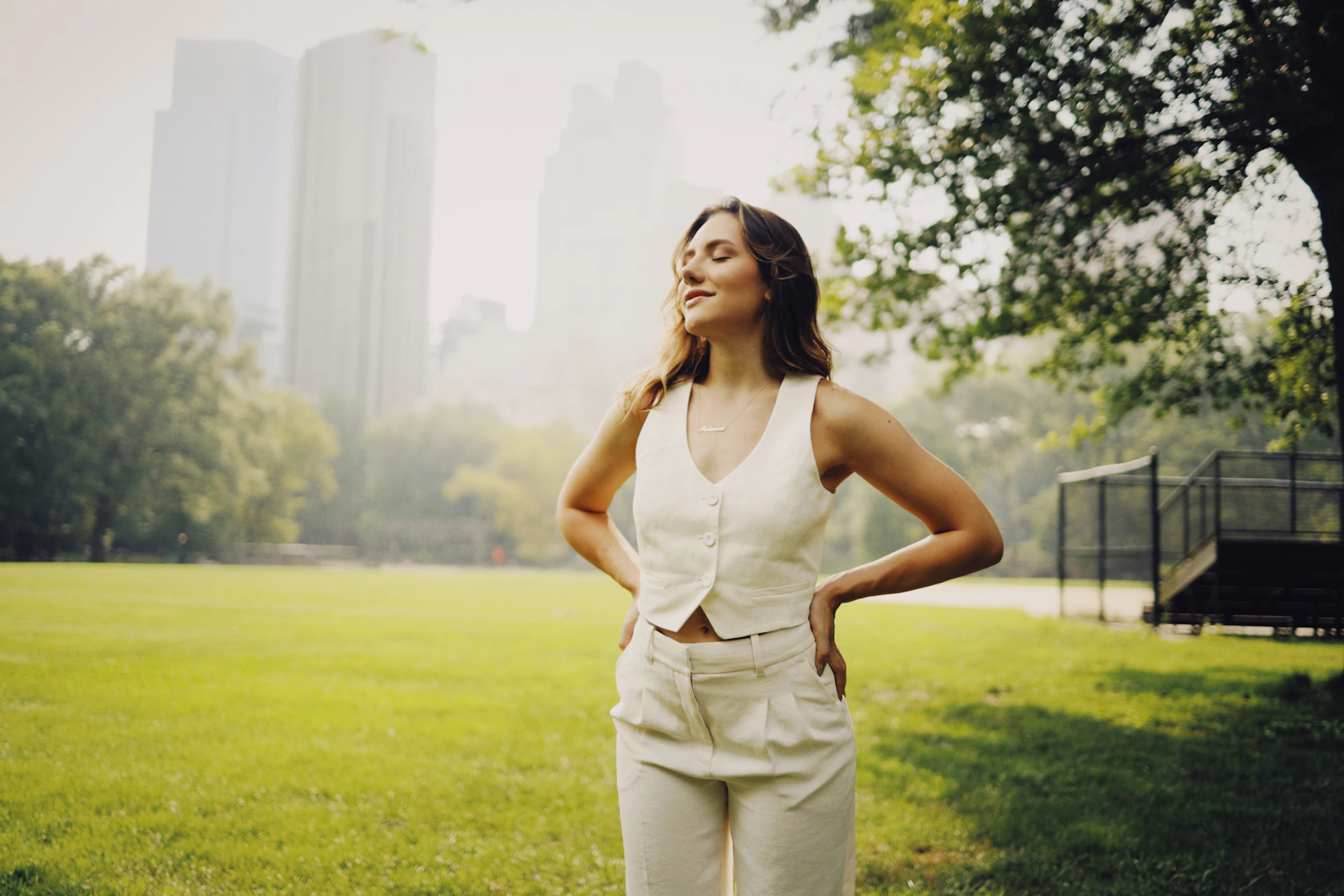 a woman standing in a park with her hands on her hips