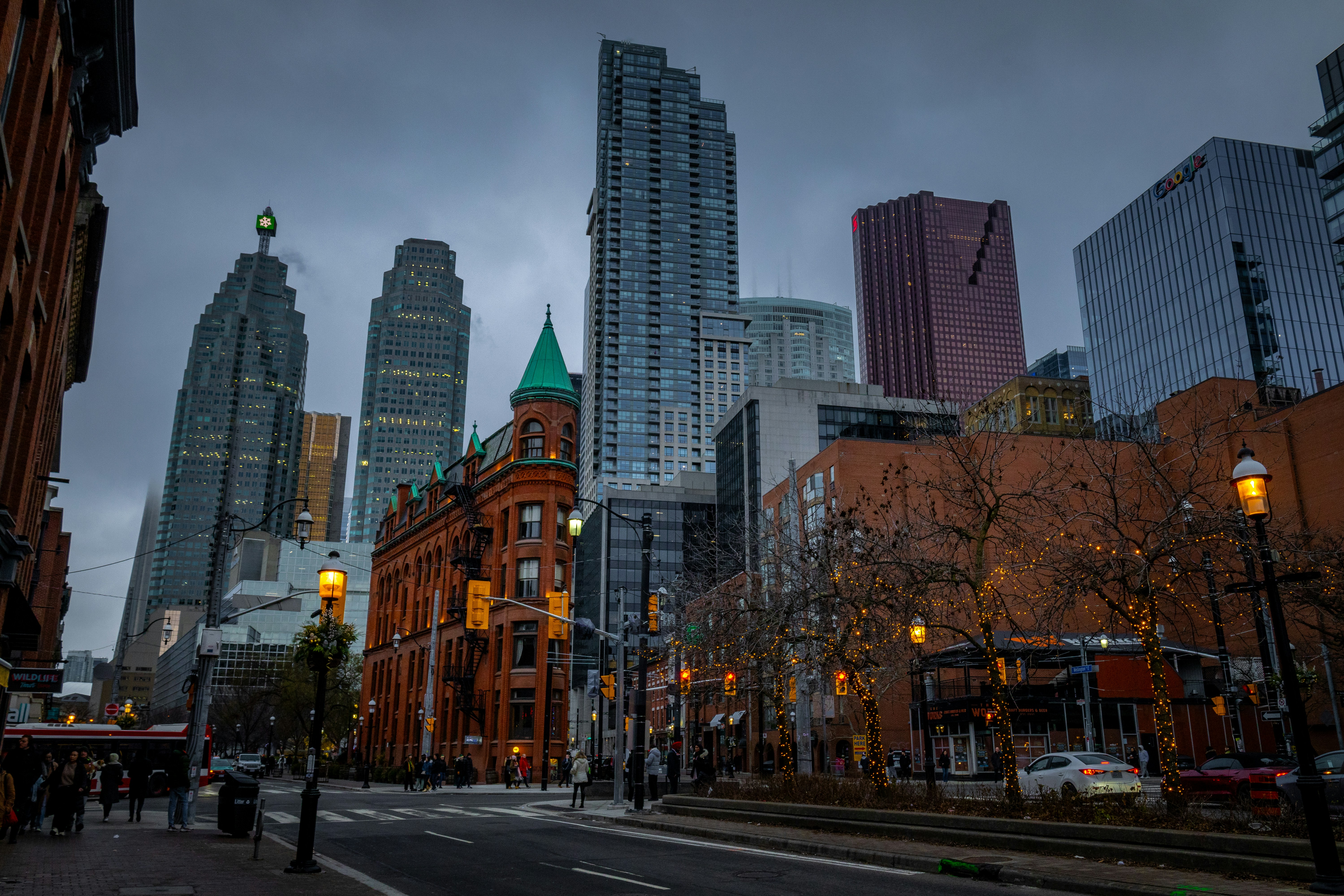 a city street with tall buildings in the background, Toronto skyscrapers with Gooderham building.