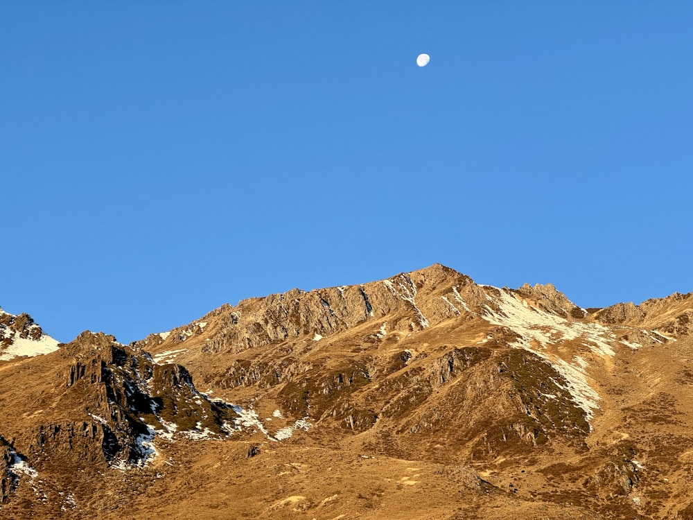 a view of a mountain with a moon in the sky