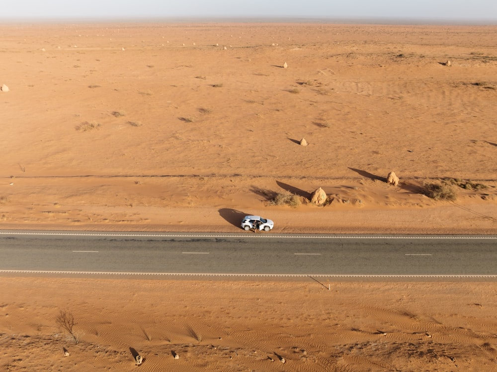 Ein Auto, das mitten in der Wüste eine Wüstenstraße entlangfährt