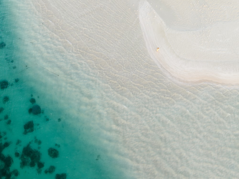an aerial view of a sandy beach and clear water