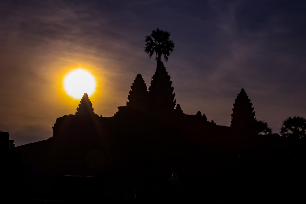 the sun is setting behind a silhouette of a building