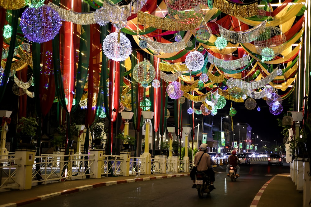 a person riding a motorcycle down a street covered in lights