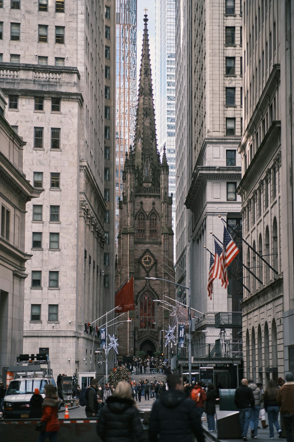 a group of people walking down a street next to tall buildings