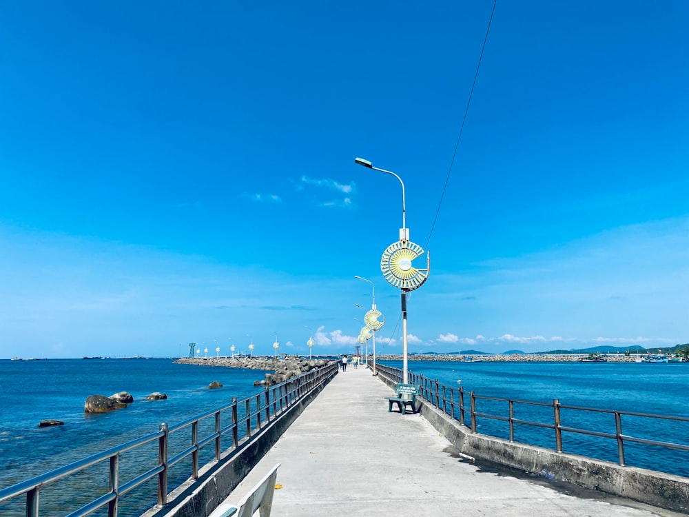 a long pier next to the ocean under a blue sky