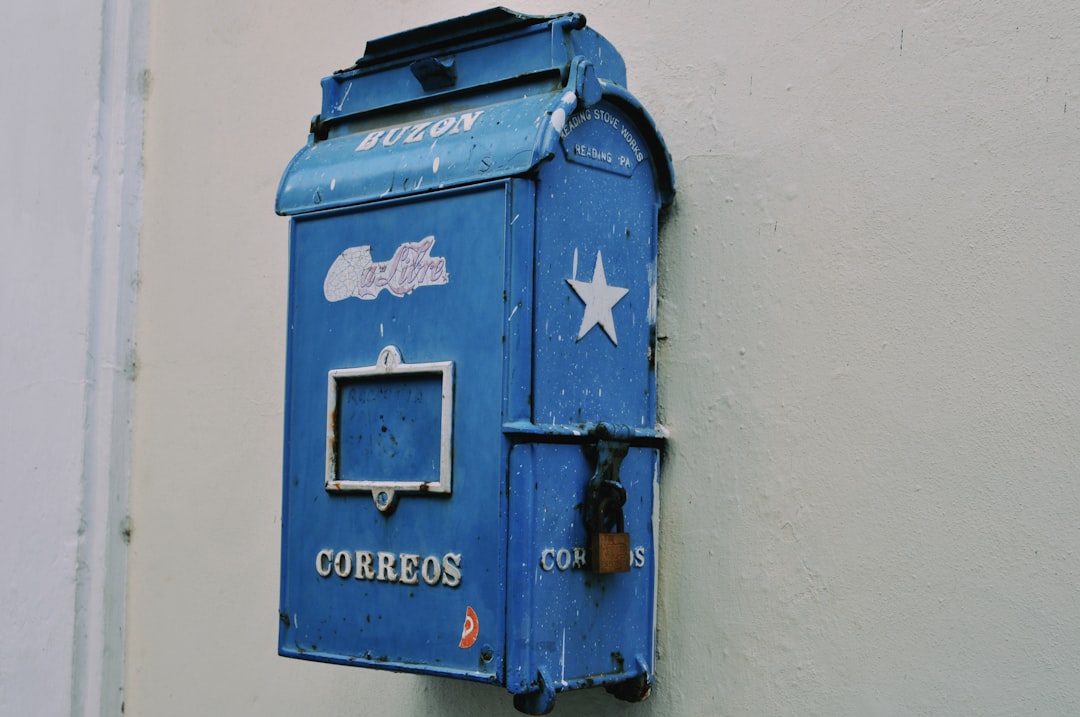 a blue mailbox mounted to the side of a building,