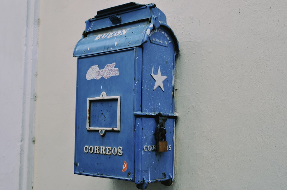 a blue mailbox mounted to the side of a building