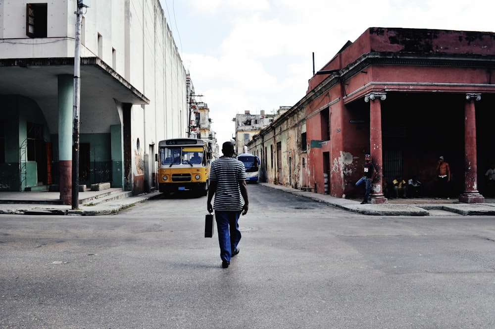 a person walking down a street in front of a bus