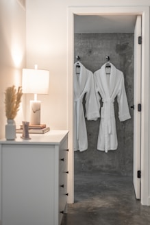 a white robe hanging on a wall next to a lamp