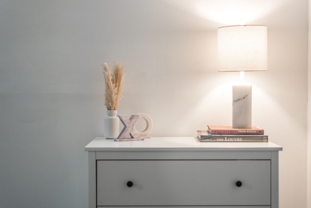 a nightstand with a lamp and books on top of it