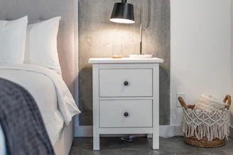 a bedroom with a bed and a nightstand with a lamp on top of it