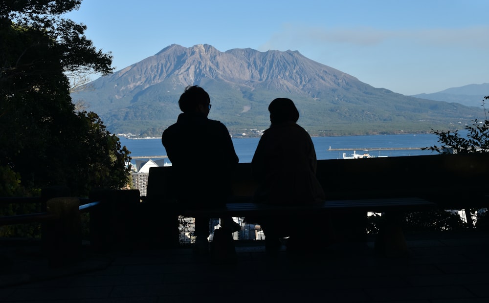 ベンチに座って山を眺める2人
