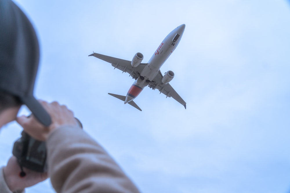 a person taking a picture of an airplane in the sky