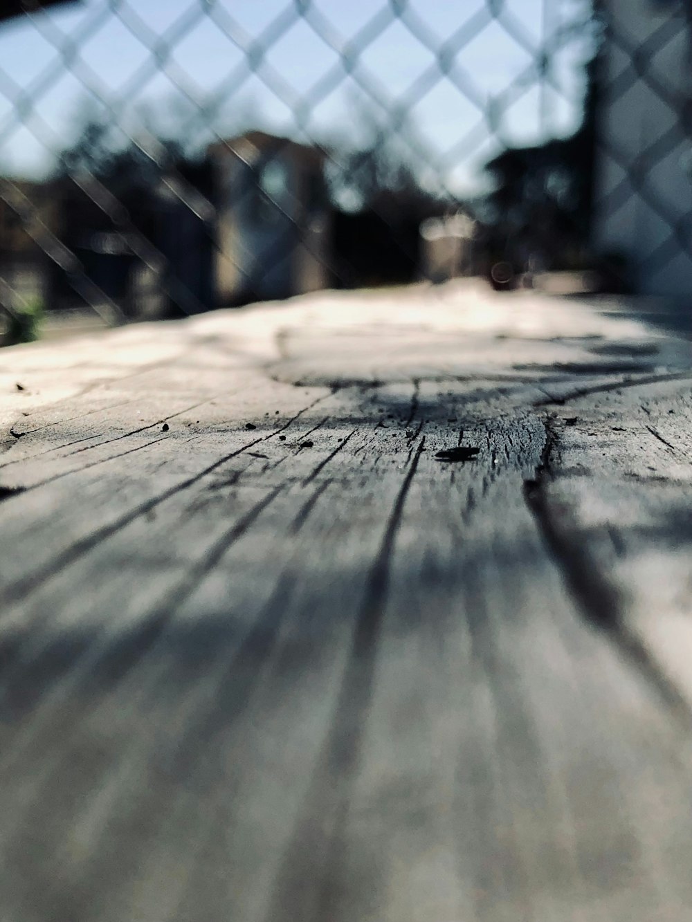 a wooden table with a chain link fence in the background