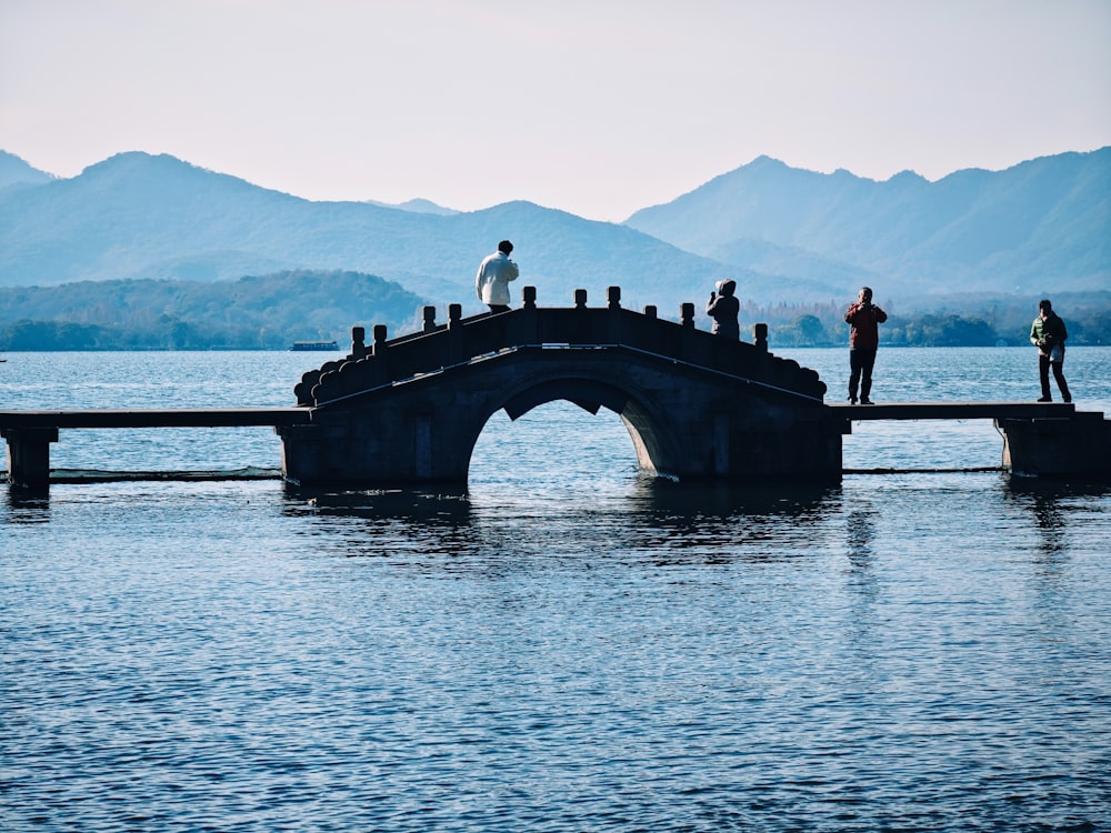 a group of people standing on a bridge over a body of water