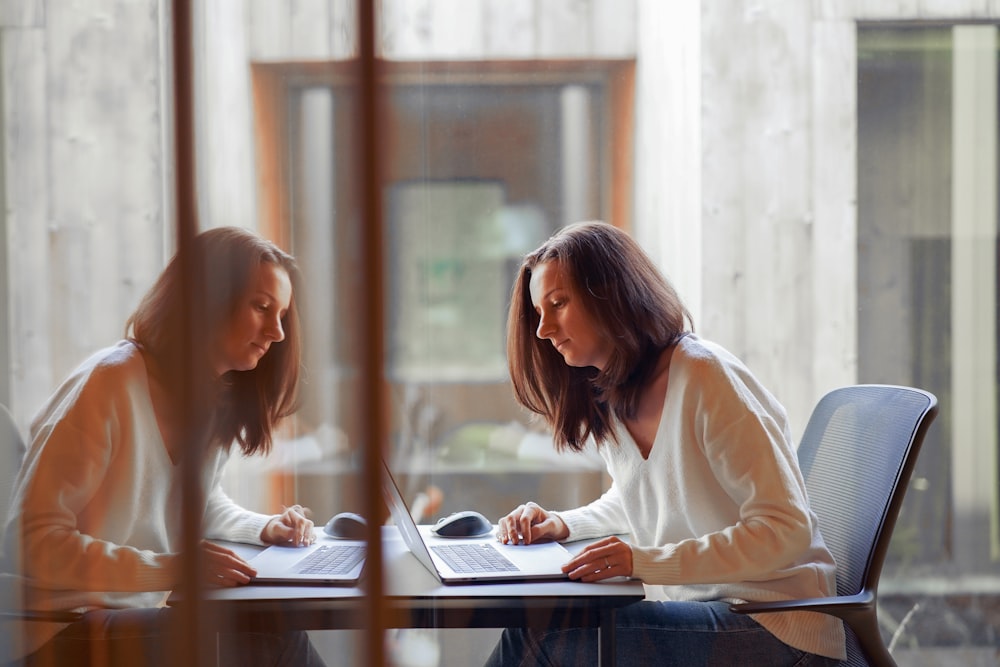 two women sitting at a table working on a laptop