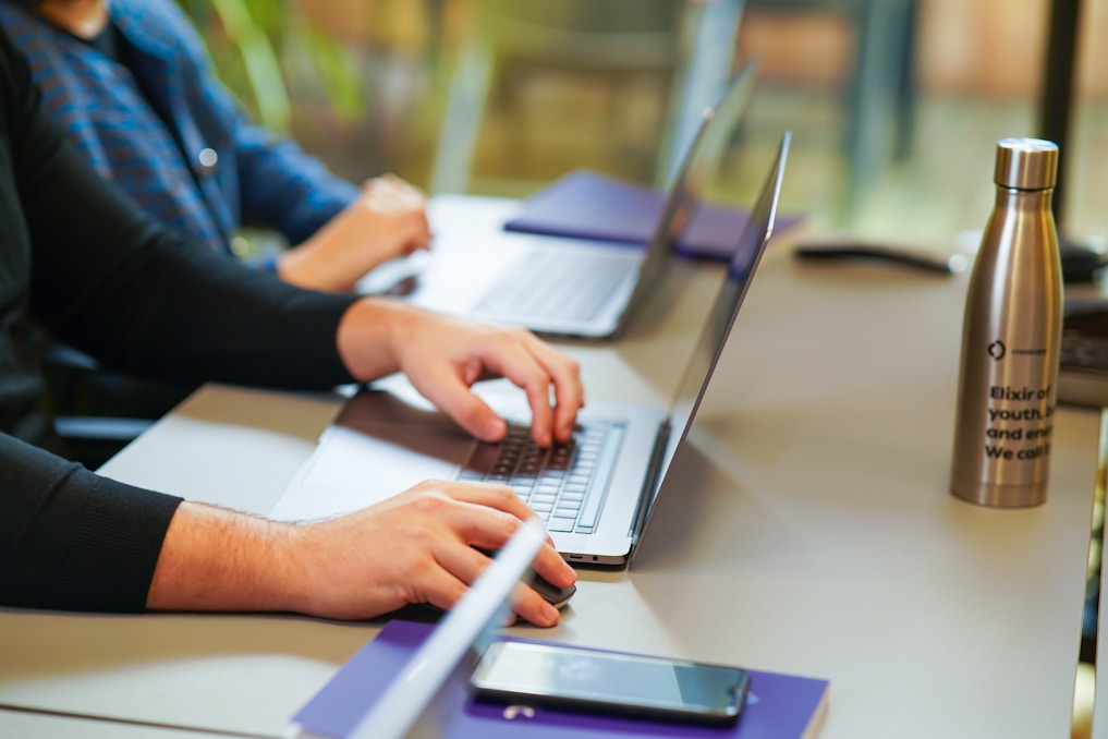 two people sitting at a table using laptops