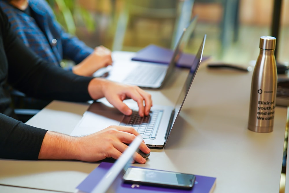 two people sitting at a table using laptops