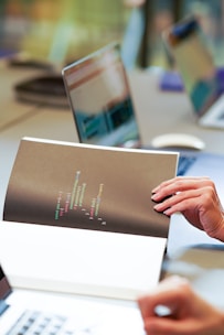 a person is holding a piece of paper in front of a laptop