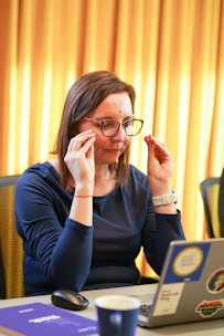 a woman sitting at a table in front of a laptop computer