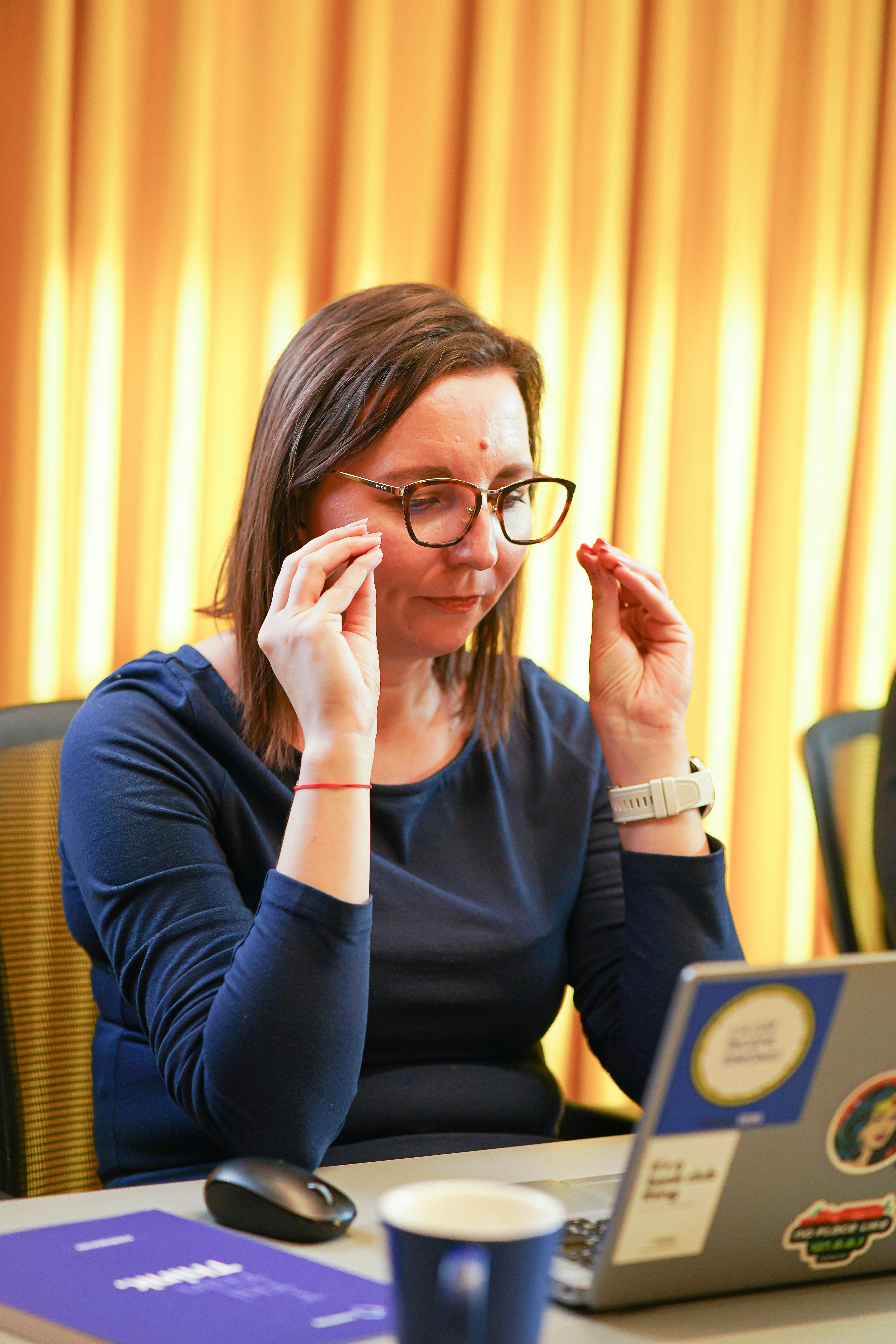 a woman sitting at a table in front of a laptop computer