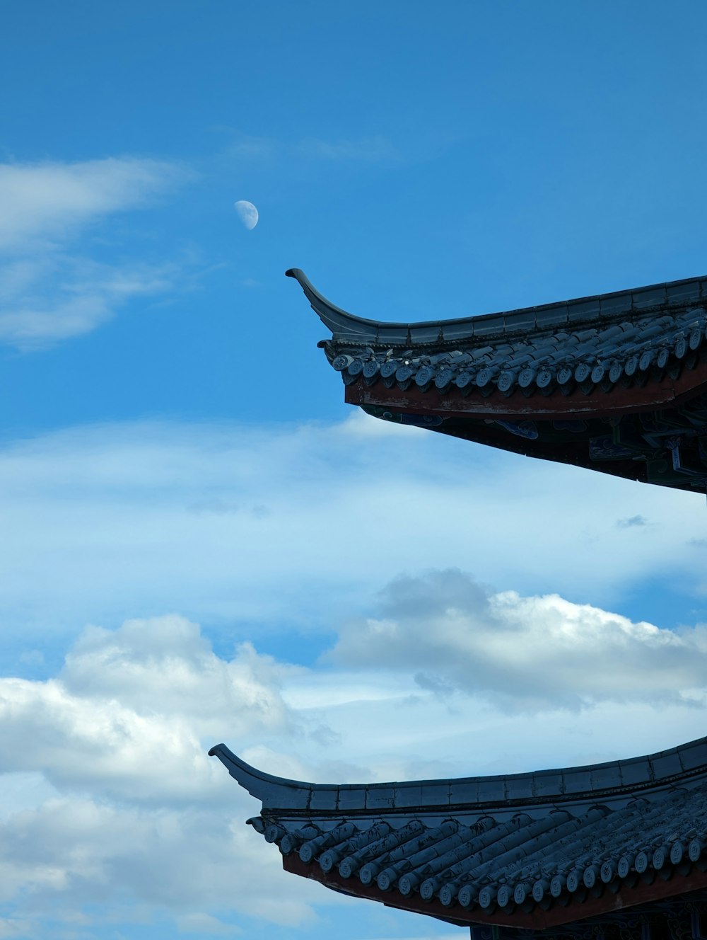 the roof of a building with a half moon in the sky