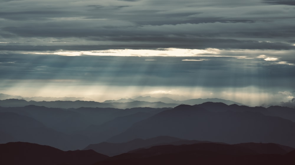 the sun shines through the clouds over the mountains