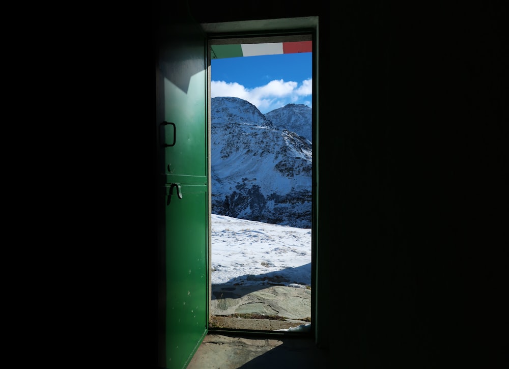 an open door leading to a snowy mountain range