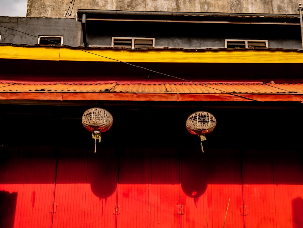 a red building with three round lamps hanging from it's side