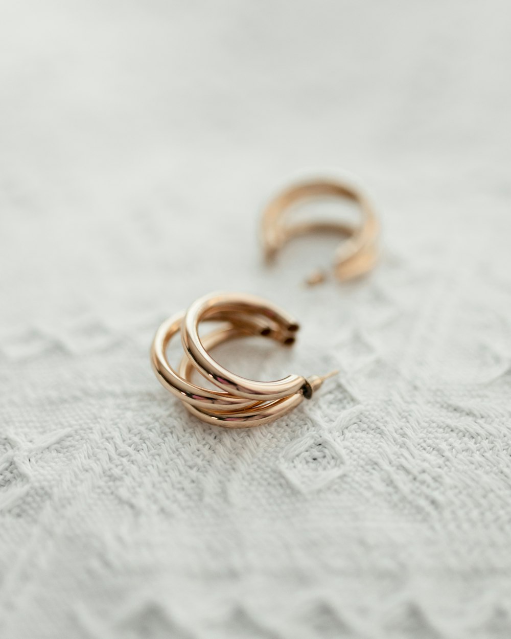 a pair of gold rings sitting on top of a white cloth