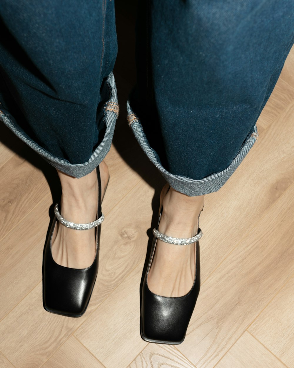 a person standing on a wooden floor wearing black shoes