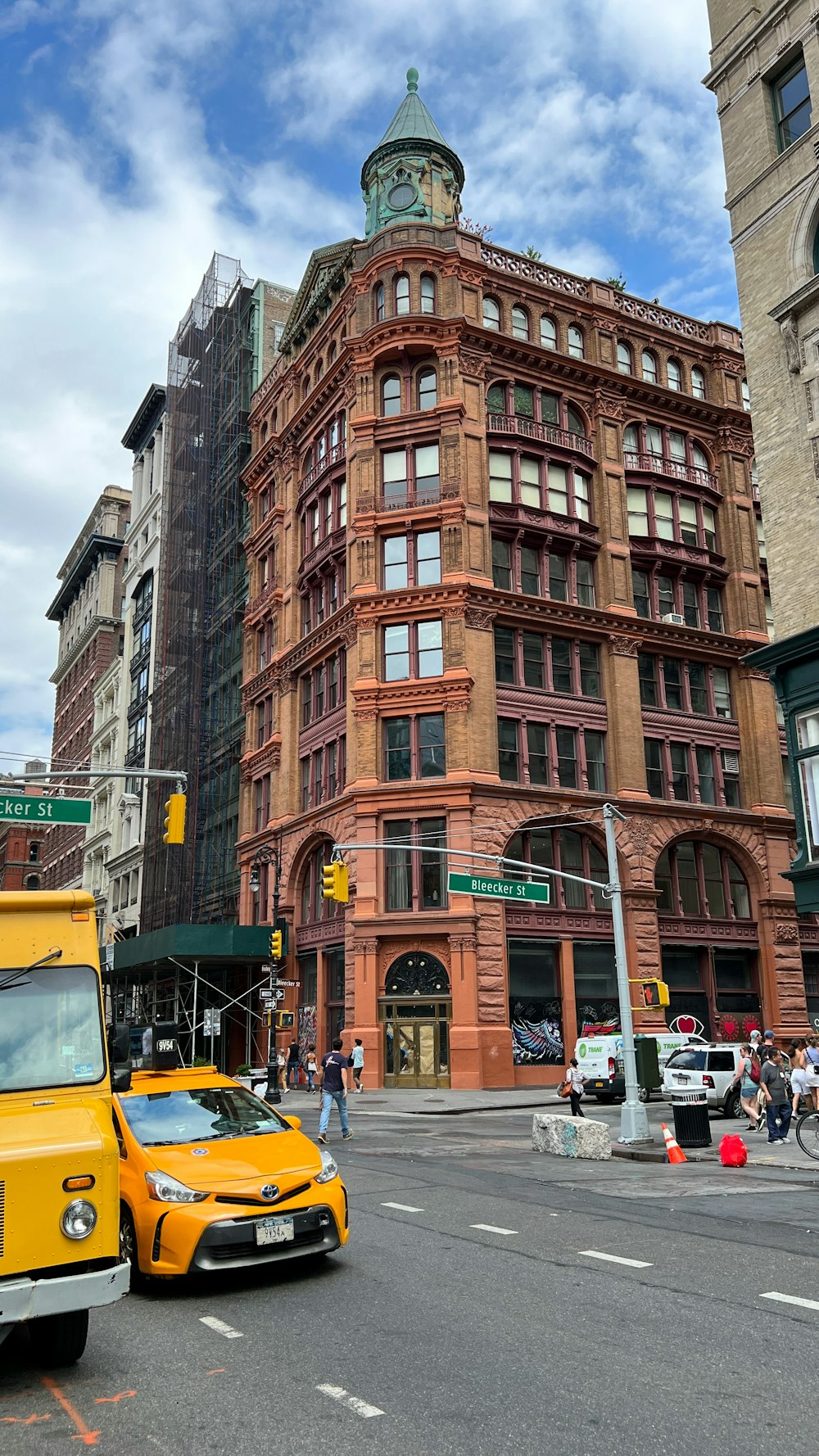 a yellow truck driving down a street next to tall buildings