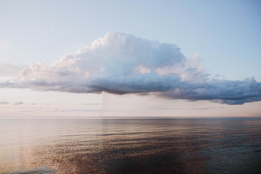 a large cloud is in the sky over the ocean