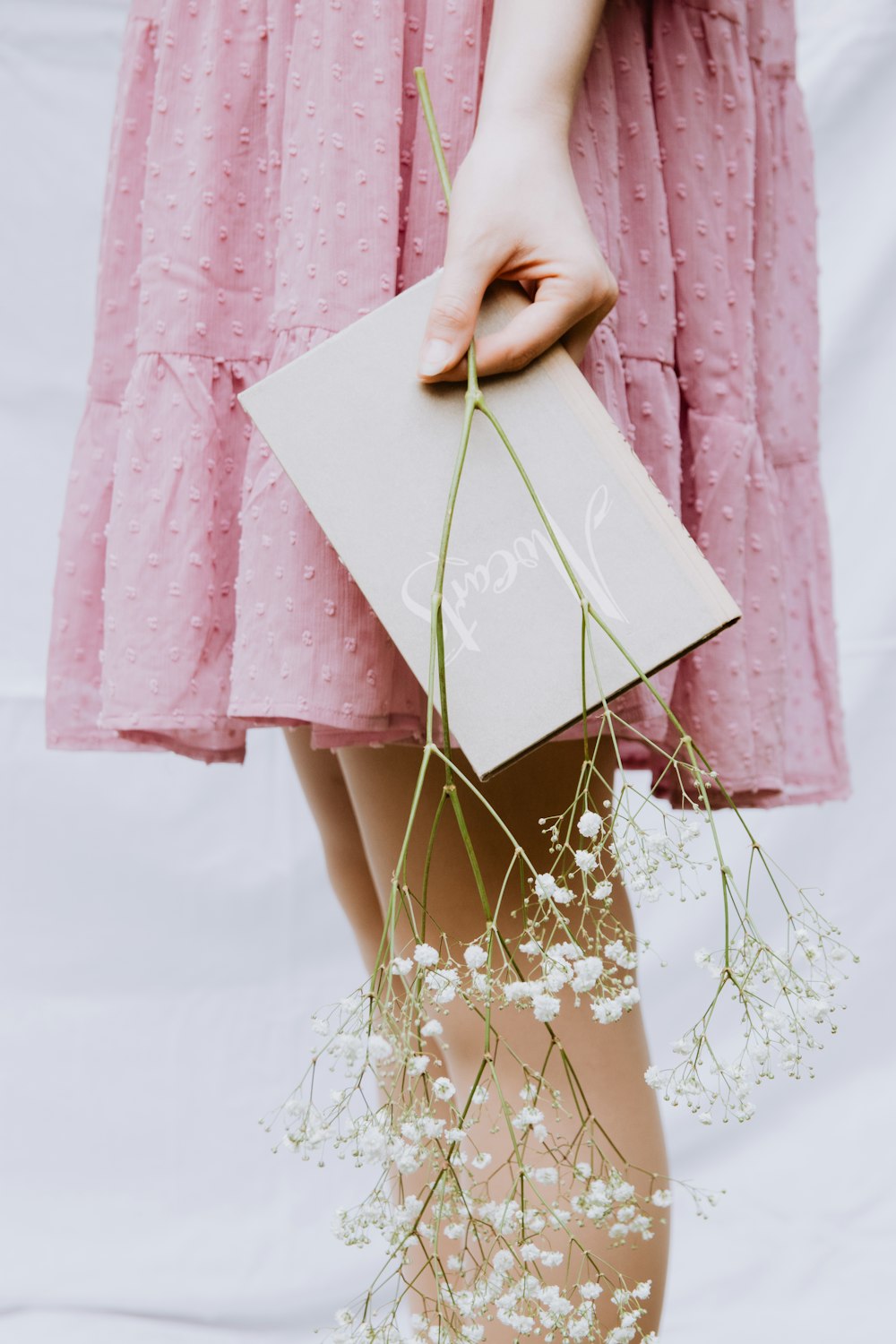 a woman in a pink dress holding a card and flowers