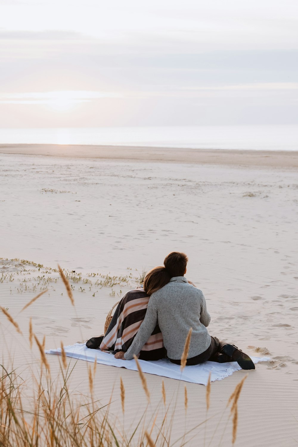 a man and woman sitting on a surfboard on the beach