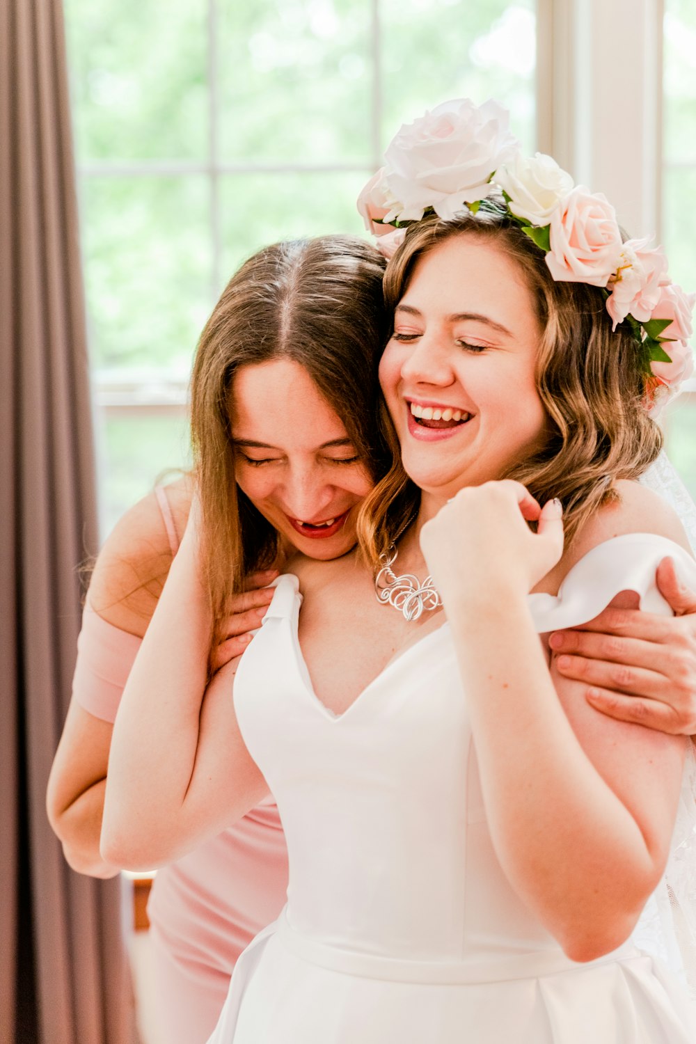 two brides hugging each other in front of a window