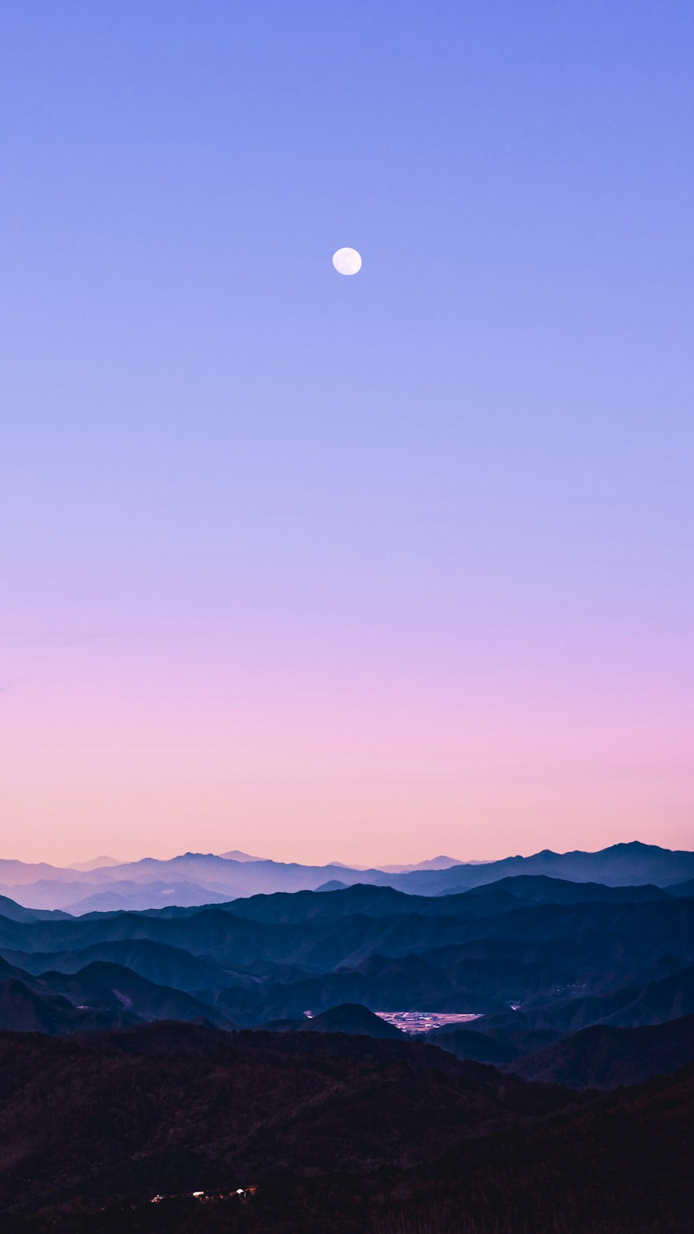 a view of a mountain range with a moon in the sky