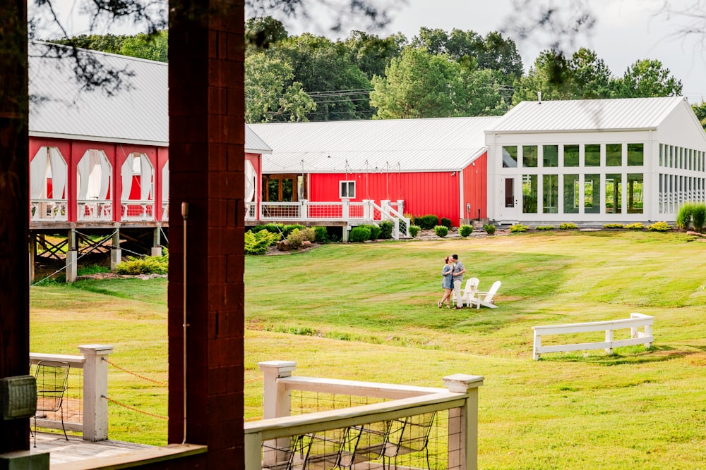 two people sitting on a bench in front of a red barn