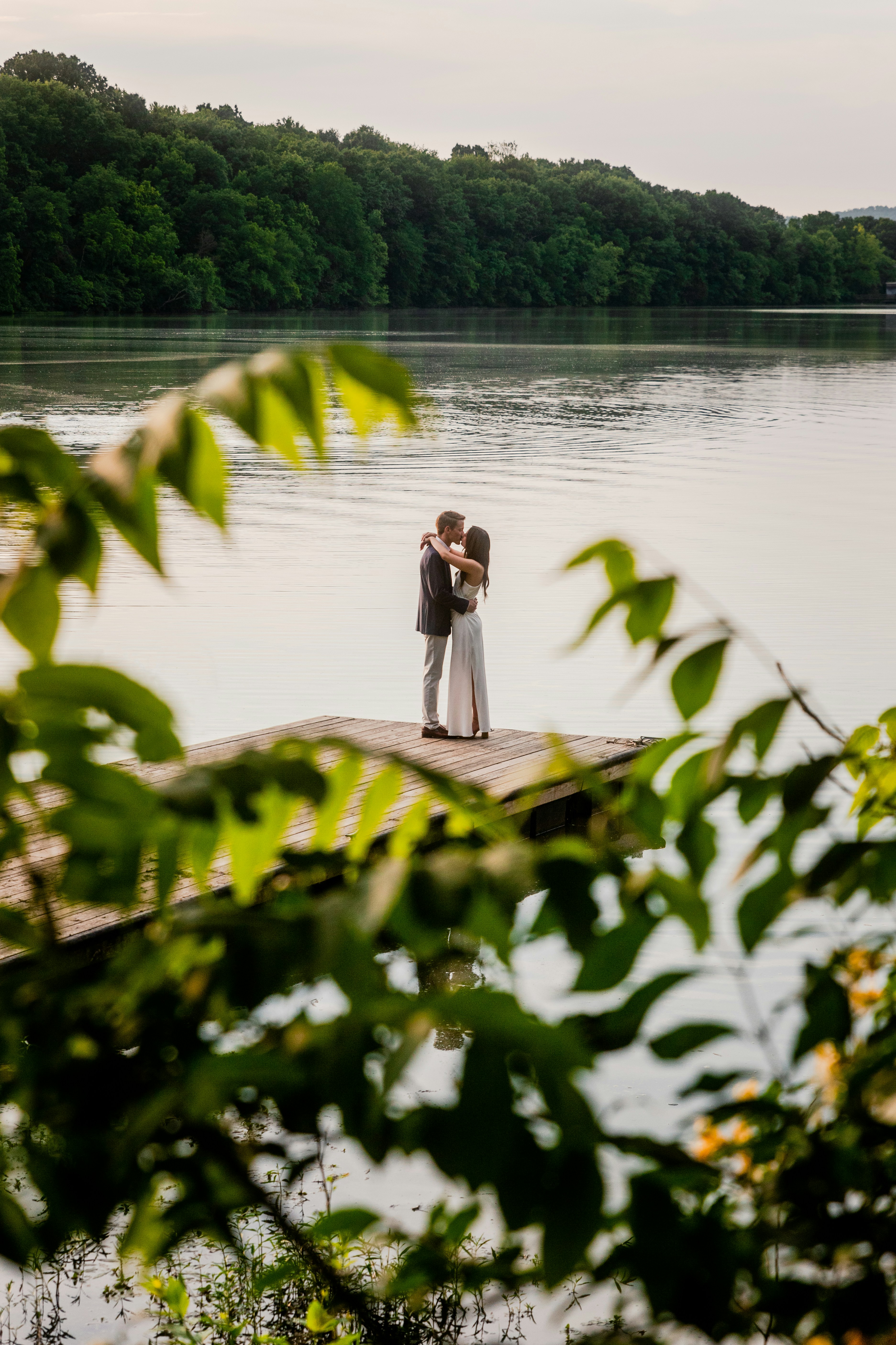 una sposa e uno sposo in piedi su un molo di fronte a un lago
