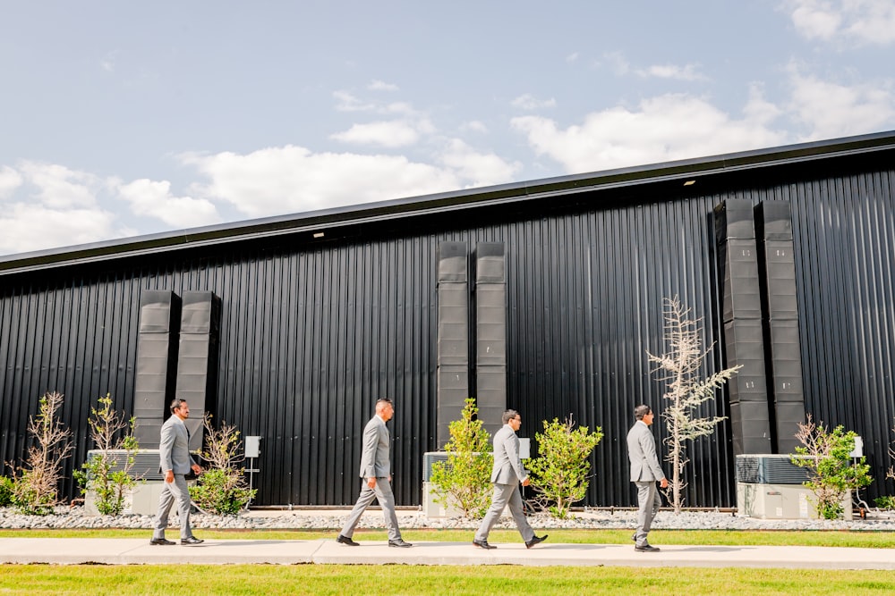 a group of men walking down a sidewalk next to a building