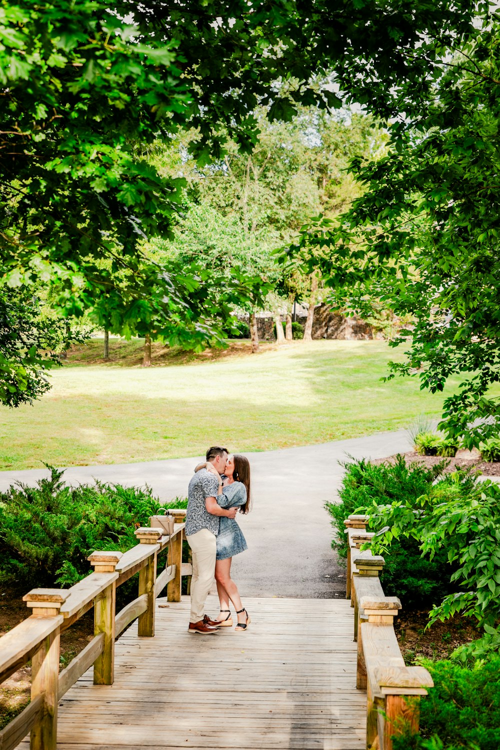 a couple kissing on a bridge in a park