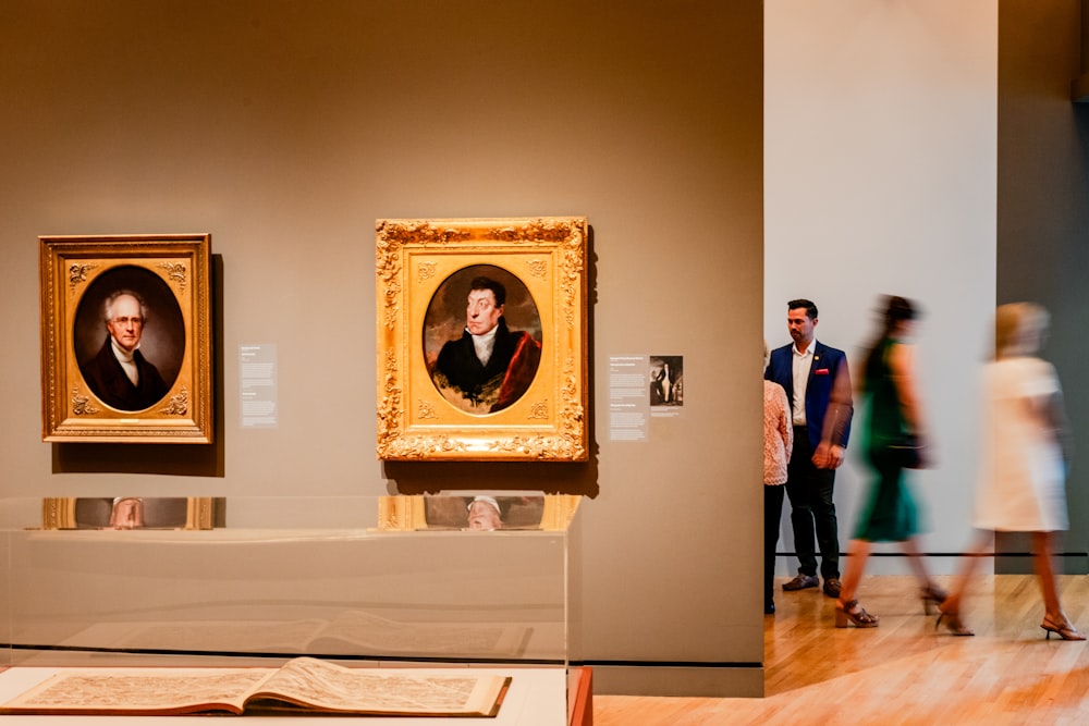 a group of people looking at paintings on display