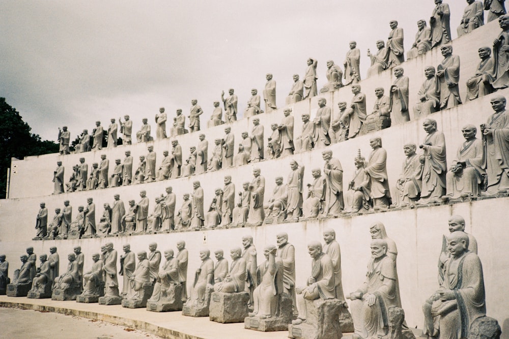 a large group of statues sitting on the side of a wall