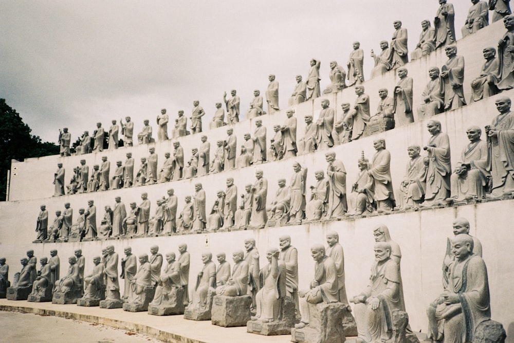 un grand groupe de statues assises sur le côté d’un mur