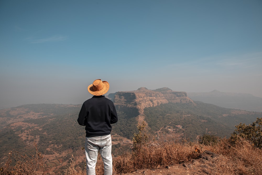 a man standing on top of a hill looking at the mountains