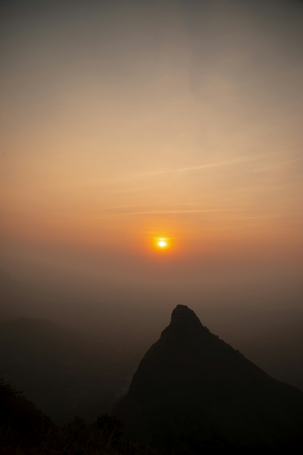 the sun is setting on a foggy mountain